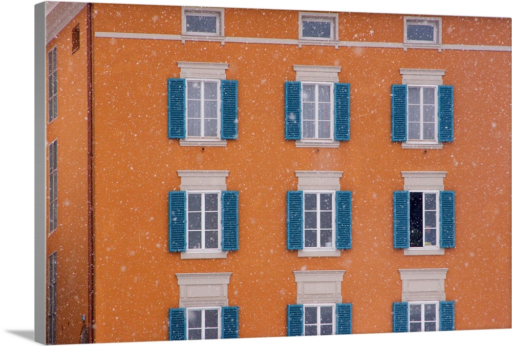 Europe, Austria, Salzburg. Blue shutters on orange apartment building in snowfall. (UNESCO World Heritage Site) Credit as:...