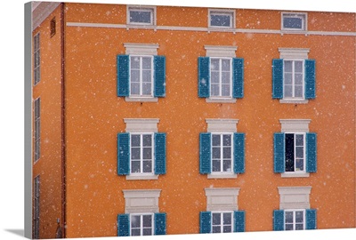 Austria, Salzburg. Blue shutters on orange apartment building in snowfall