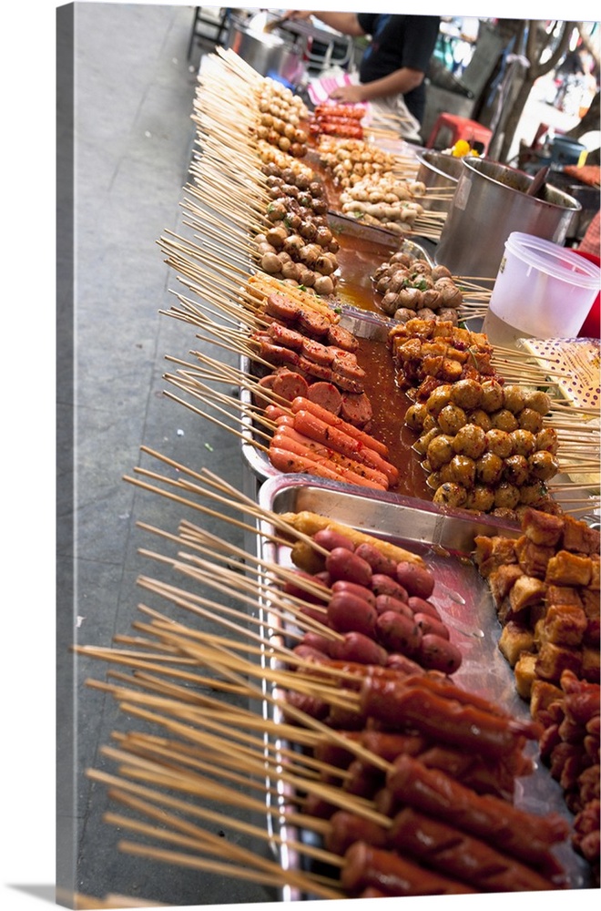 Bangkok, Thailand - Tilted view of a street vendor selling various Thai foods on wood skewers. Vertical shot.