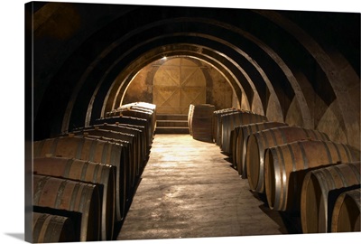 Barrel aging cellar with lines of barriques and dramatic lighting, France