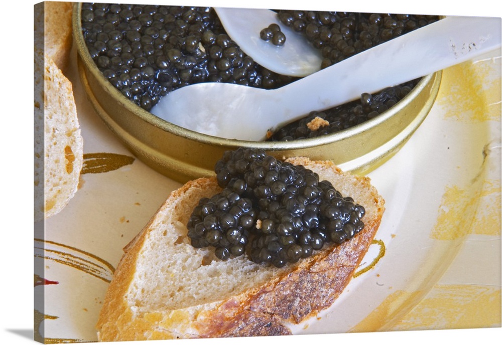 A tin of black caviar with slices of bread and a spoon of mother-of-pearl to scoop up the precious eggs, caviar on a piece...