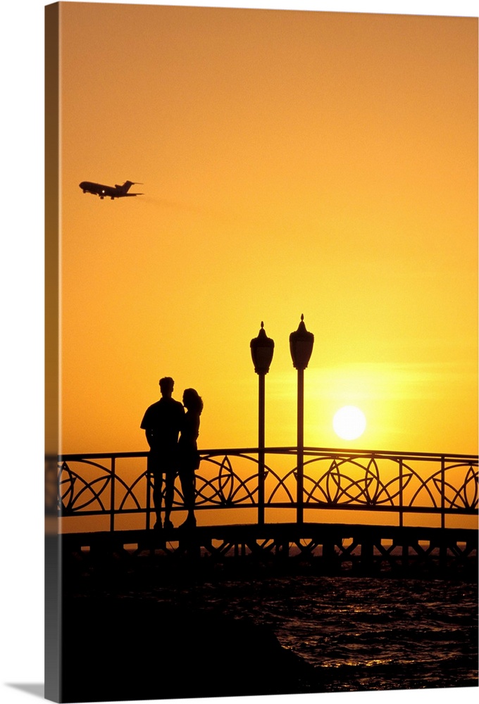 Caribbean, Aruba, Oranjestad. Couple enjoying sunset with plane overhead