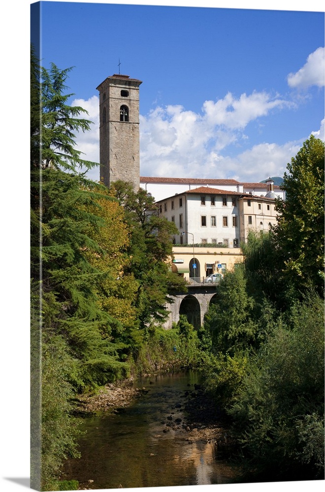 Castelnuovo di Garfagnana, Tuscany, Italy - Old world buildings as seen behind a small waterway and trees. Vertical shot.