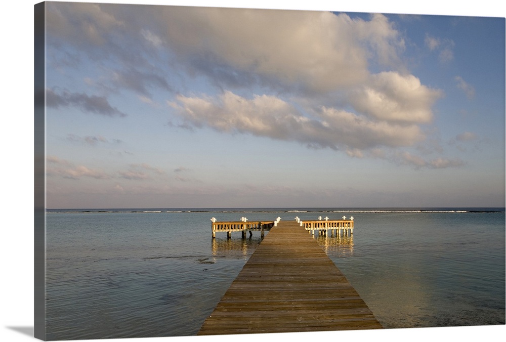 Cayman Islands, Little Cayman Island, Setting sun lights wooden boat pier in Caribbean Sea