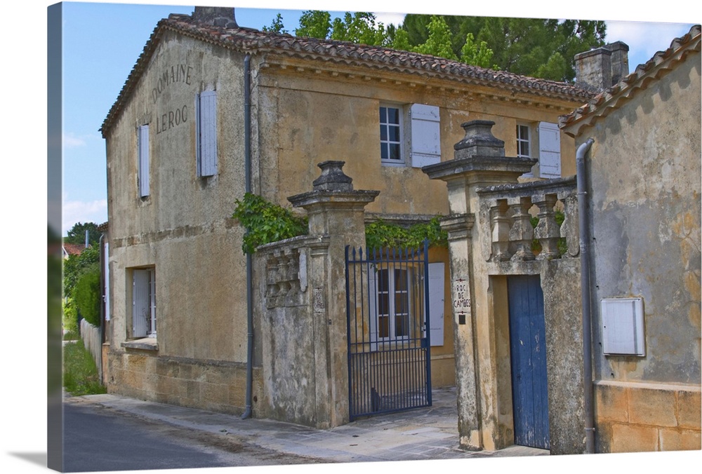 The Chateau Roc de Cambes with stone wall iron gate and stone gate posts with the name carved. Blue doors and yellow house...