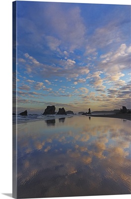Clouds reflect in wet sand at sunrise at Bandon Beach in Bandon, Oregon