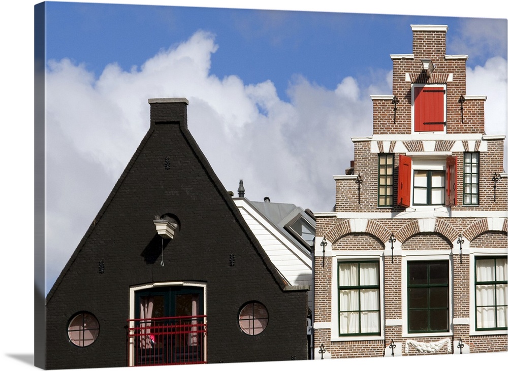 Colorful buildings with ornate facades and windows with red shutters against a blue sky with fluffy white clouds