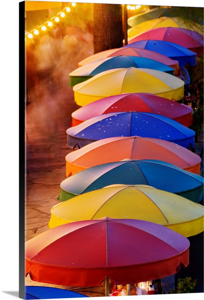 Colorful umbrellas of outdoor cafe and blurred people in motion along famous River Walk and San Antonio River, San Antonio...