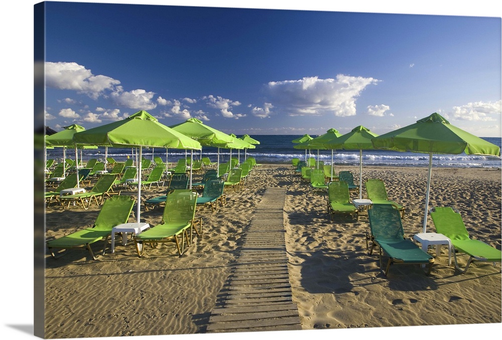 Greece and Greek Island of Crete with the city of Rethimnon with green umbrellas and lounges on the beach for the many arr...