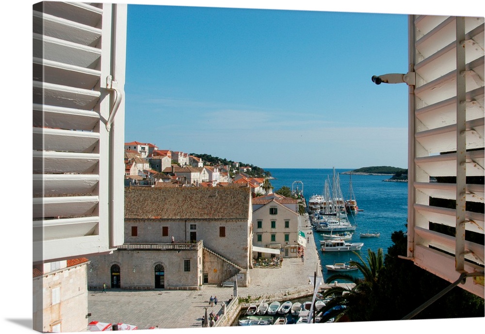 Croatia, Dalmatian Coast, Hvar, view of the harbor, boats and Riva seen thru shuttered windows of Palace Hotel