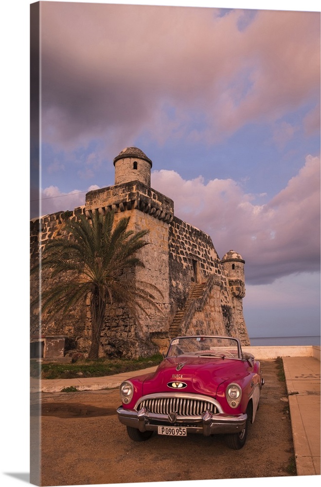 Cuba, Cojimar. Classic American car parked in front of a fort.