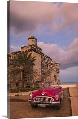 Cuba, Cojimar, Classic American car parked in front of a fort