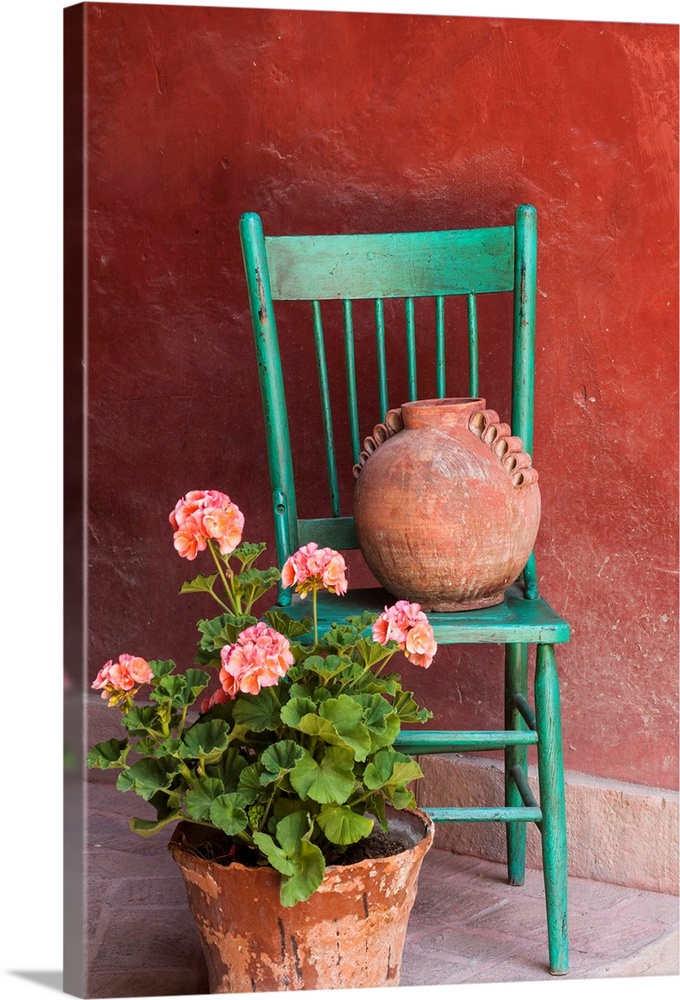 Mexico, San Miguel de Allende. Geraniums, flowerpots and chair decorate an entrance.