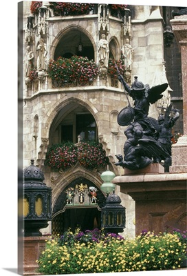 Germany, Munich, Marienplatz, Statue and flowers in front of Glockenspiel