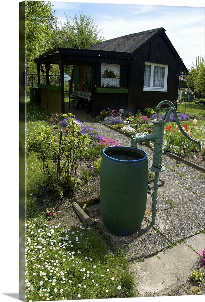 Germany, Straubing, water barrel and pump in cottage garden in Spring