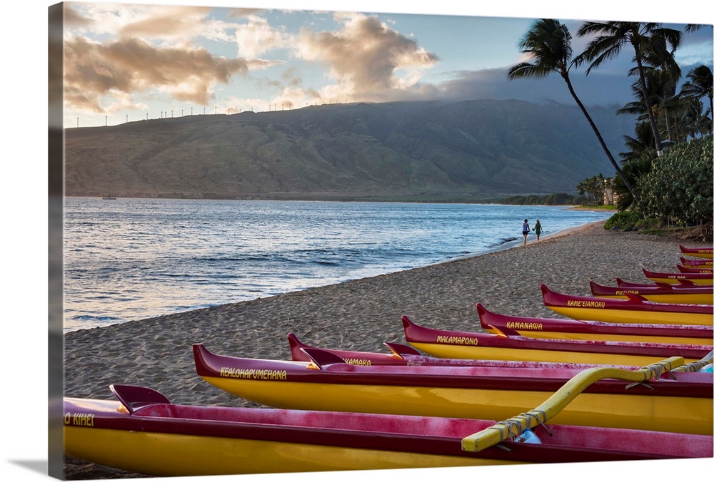 Hawaii, Maui, Kihei. Traditional Hawaiian outrigger canoes in the foreground with people on Ka Lae Pohaku beach and palm t...