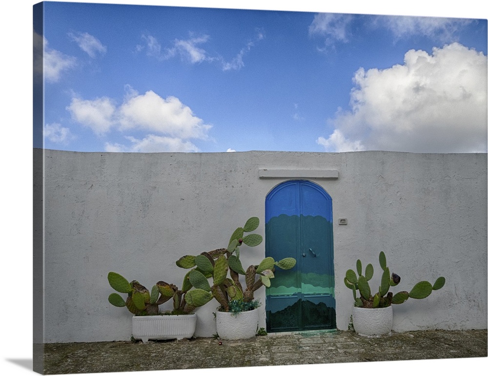 Italy, Puglia, Brindisi, Itria Valley, Ostuni. Bright blue door along a white wall. On either side of the door are potted ...