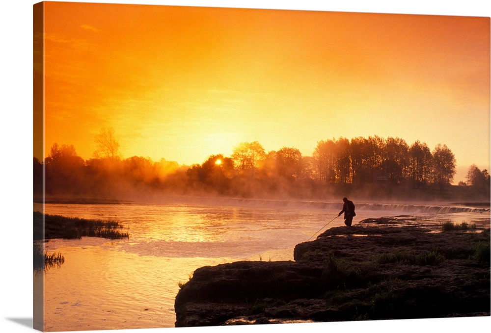 Fisherman at sunrise on Venta River waterfall at city of Kuldiga in Kurzeme region of Latvia.