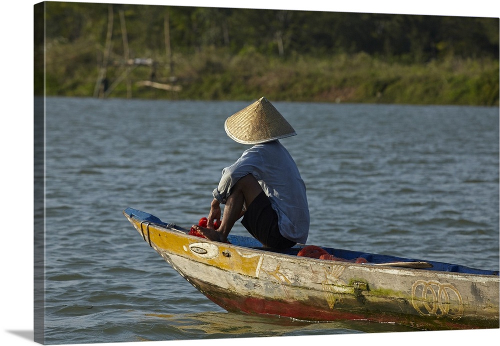 Man fishing from boat on Thu Bon River, Hoi An (UNESCO World Heritage Site), Vietnam