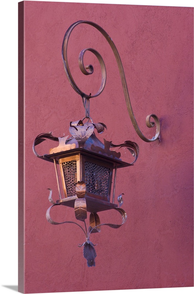 Mexico, San Miguel de Allende. Ornate copper lamp hung from pink-purple wall.