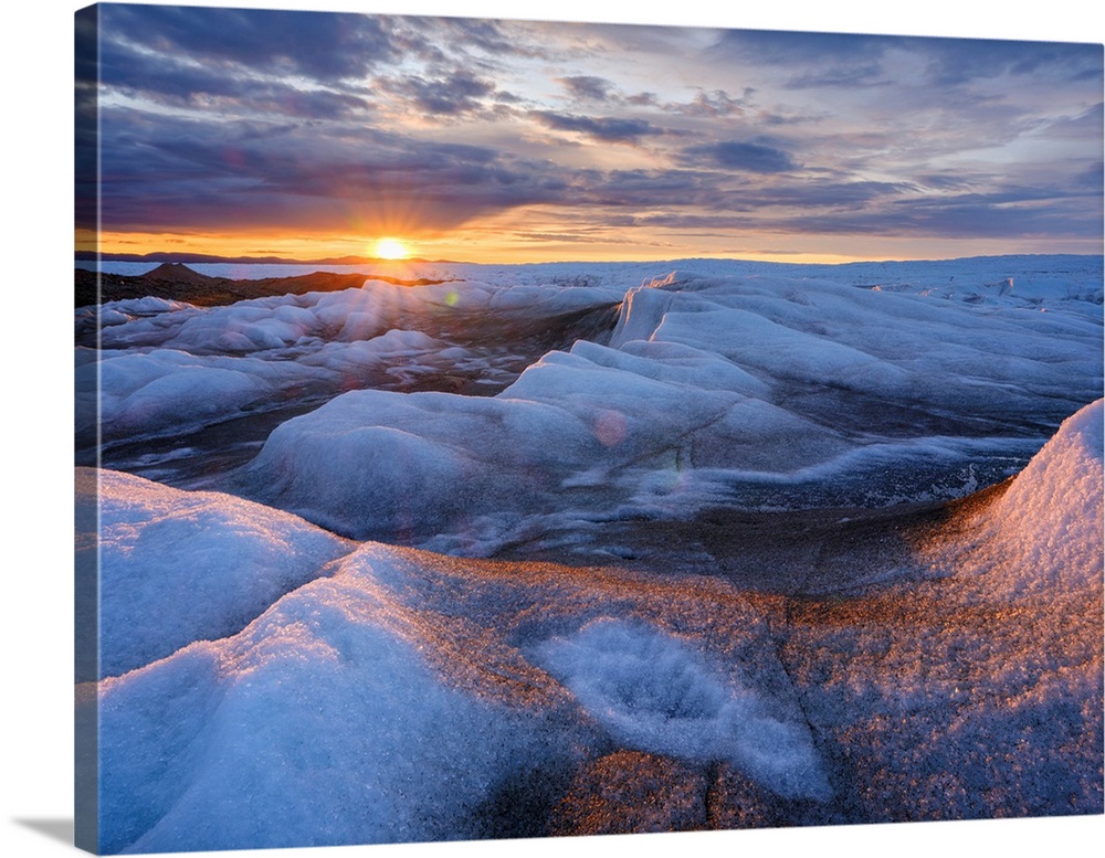 Midnight sun on the ice sheet. The brown sediment on the ice is created by the rapid melting of the ice. Landscape of Gree...