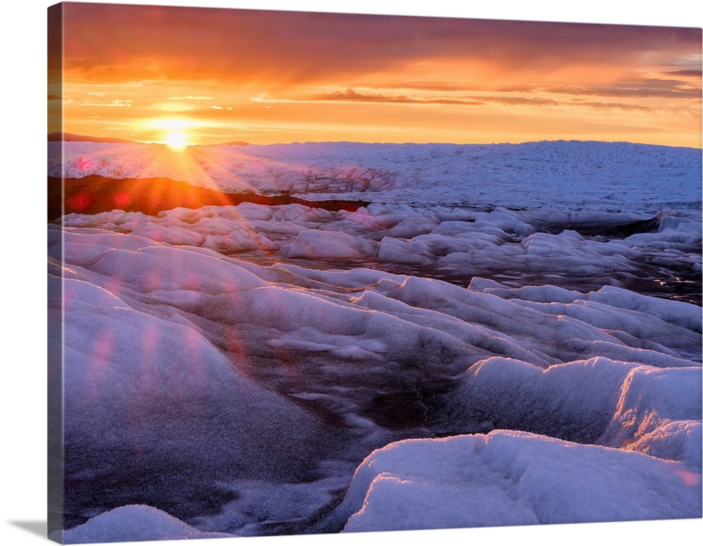 Midnight sun on the ice sheet. The brown sediment on the ice is created by the rapid melting of the ice. Landscape of Gree...