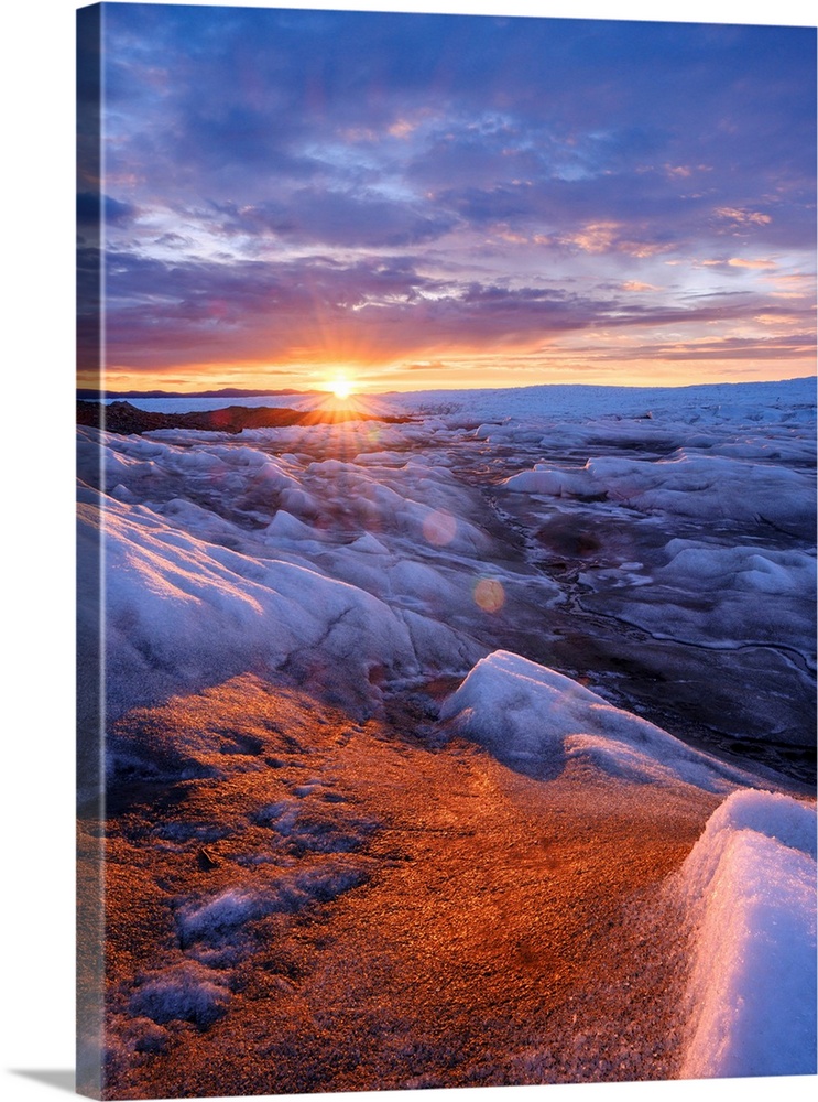 Midnight sun on the ice sheet. The brown sediment on the ice is created by the rapid melting of the ice. Landscape of Gree...