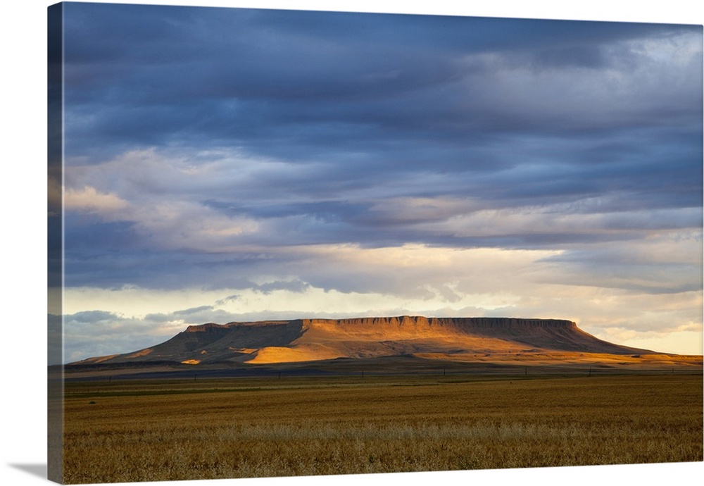 Morning sunlight breaks through the cloud cover and illuminates Square Butte near Great Falls, Montana, USA