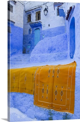 Morocco, Chefchaouen, Rugs draped on a wall in the blue town