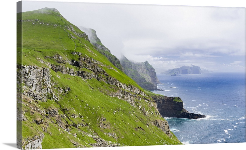 The island Mykines,in the background the island Vagar, part of the Faroe Islands in the North Atlantic. Europe, Northern E...