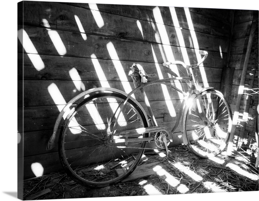 Old bicycle inside barn with shadows streaming.