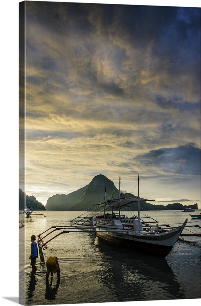 Outrigger at sunset in the bay of El Nido, Bacuit Archipelago, Palawan, Philippines.