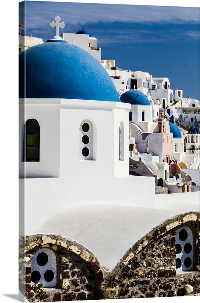 Oia, Greece. Row of Greek Orthdox Churches with blue domes and painted pastel white washed buildings.