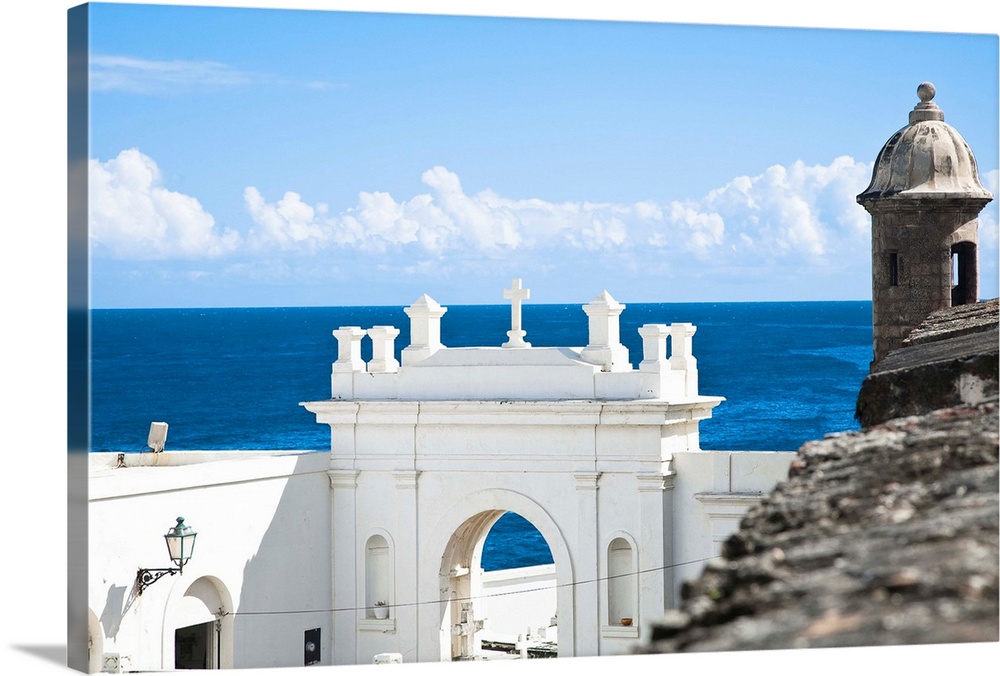 San Juan, Puerto Rico - A white building holds the entrance to a cemetery while above is an ancient fort defensive watchto...