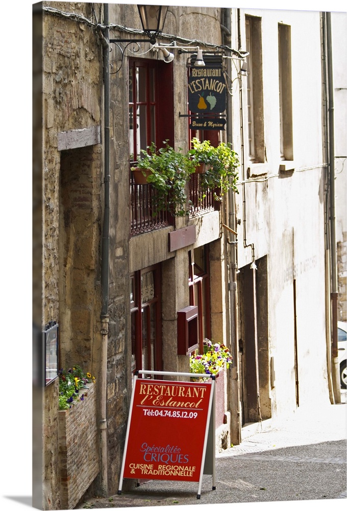 A street scene in Vinenne, a restaurant called lEstancot in the old town, with a sign and flowers in the window.  Vienne, ...