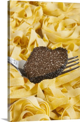 Summer black truffle on a fork with pasta background