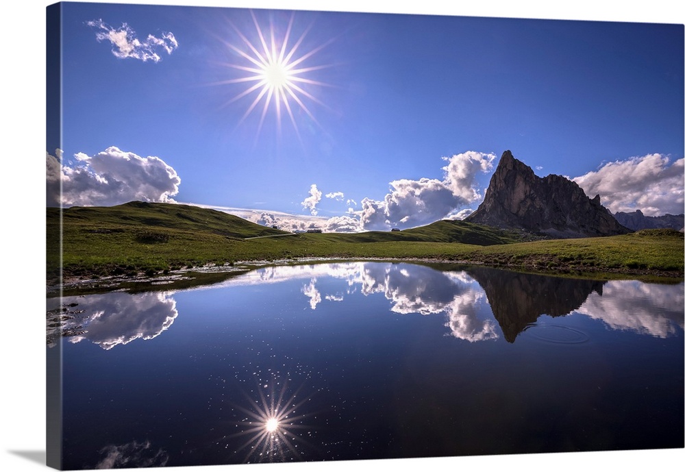 Italy, Dolomites, Giau Pass. Sun reflection in mountain tarn. Credit: Jim Nilsen