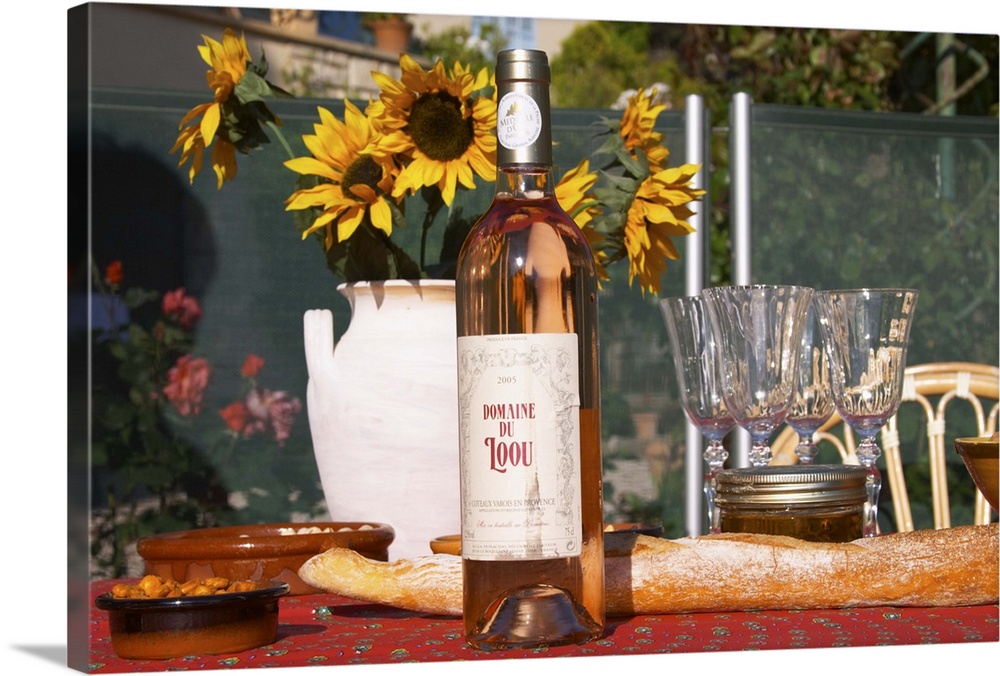 table with wine aperitif and appetizers penuts olives, flowers, typical provencal table cloth, bottle of Domaine Loou rose...