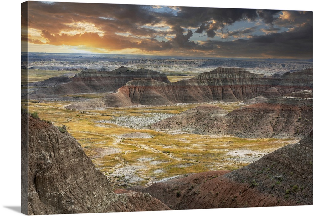The pink striped peaks or hoodoos are layered with a grass valley, at sunset.