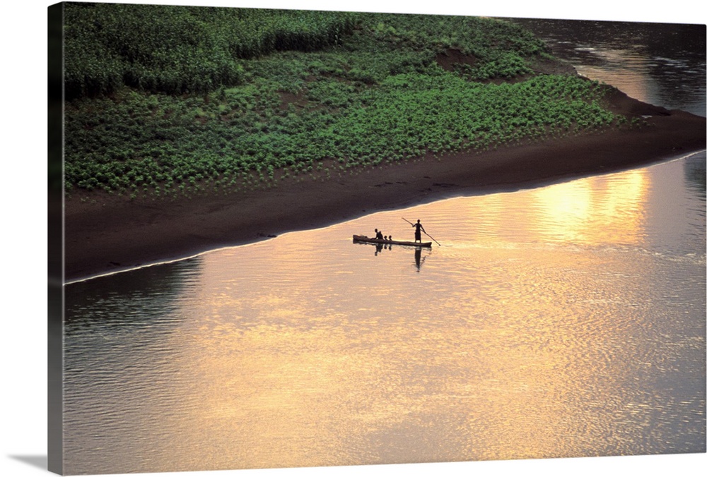 The sun sets on some Karo men piloting a dugout raft across the Omo River, near their village in Ethiopia, Africa.