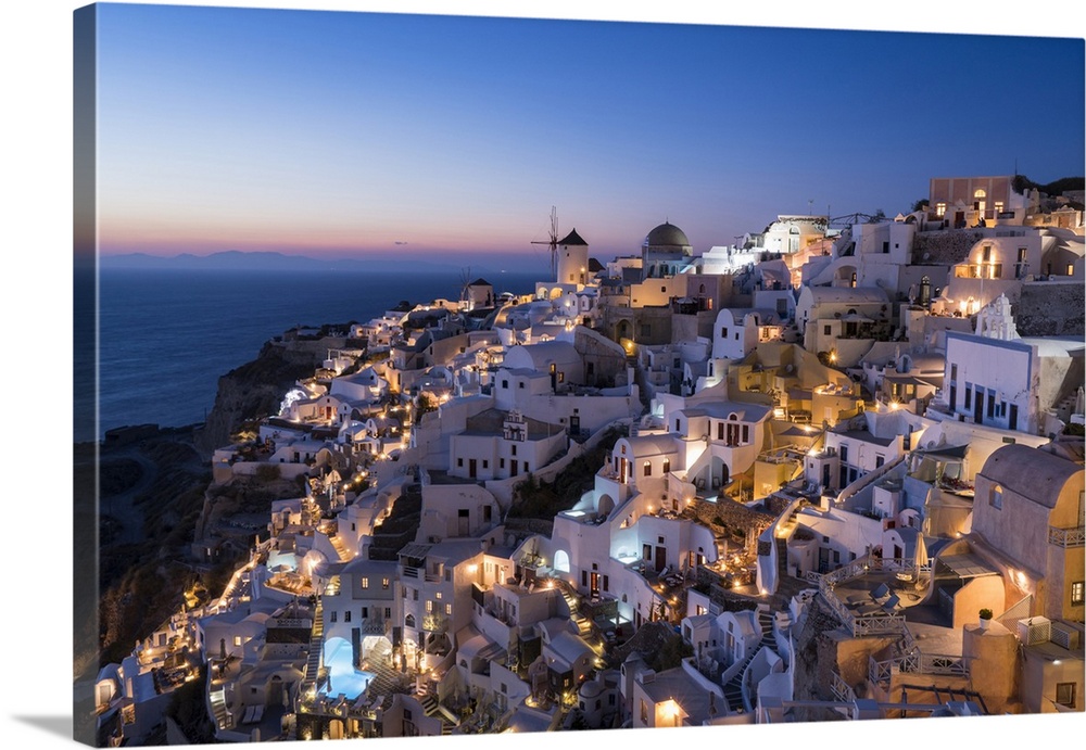 Greece, Santorini. The village of Oia glows in the post-sunset light as the town's lights add magic to this iconic scene.