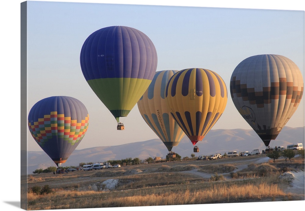 Turkey,Anatolia,Cappadocia, Goreme. Hot air balloons at lift-off, preparing to fly above/among rock formations and field l...