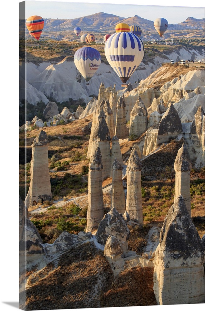 Turkey,Anatolia,Cappadocia, Goreme. Hot air balloons flying above/among rock formations, ""Fairy Chimneys"" and field land...