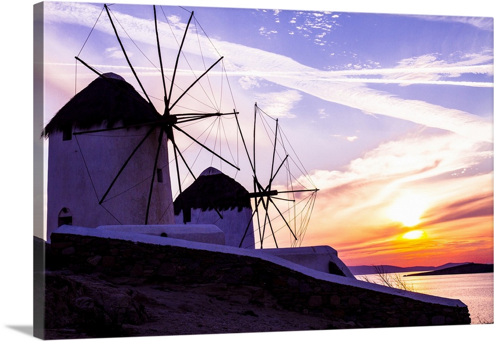 Mykonos, Greece. Two Windmills with a golden, pink, and blue sunset on the Aegean Sea.