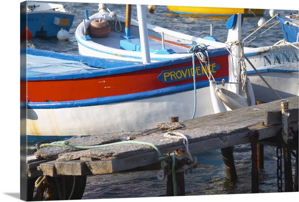 Typical Provencal fishing boats painted in bright colours white, blue, green red yellow, moored at a jetty Le Brusc Six Fo...