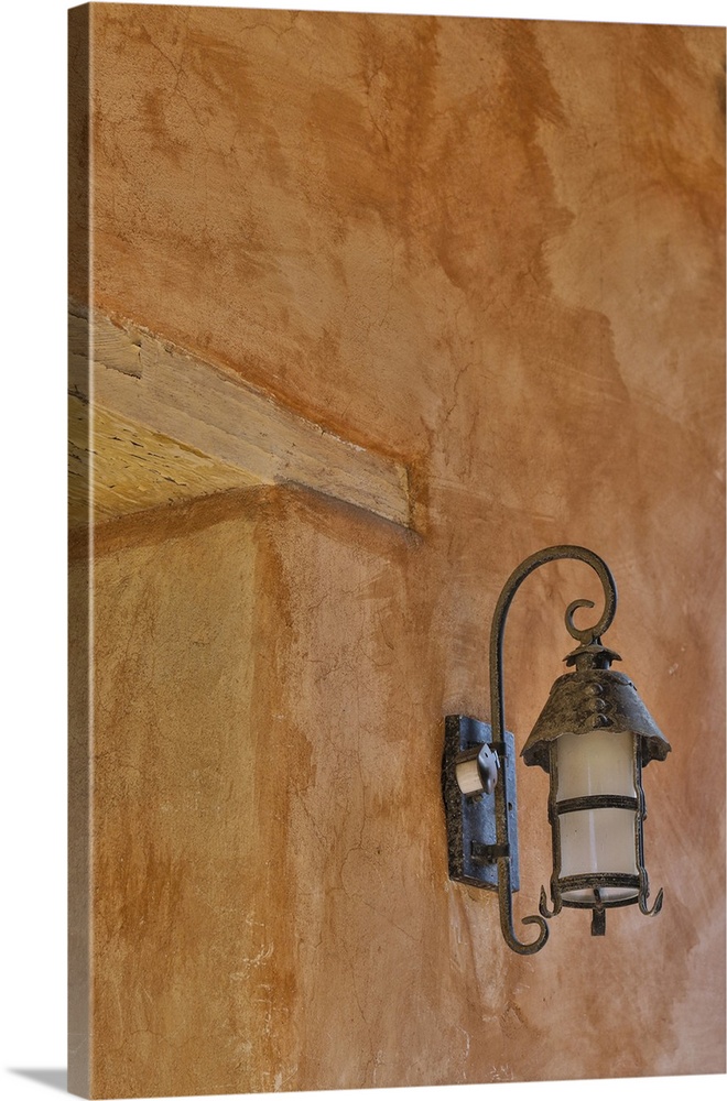 USA, California, Carmel. Inside the grounds at the Carmel Mission Basilica Museum old iron lamp on stucco wall.