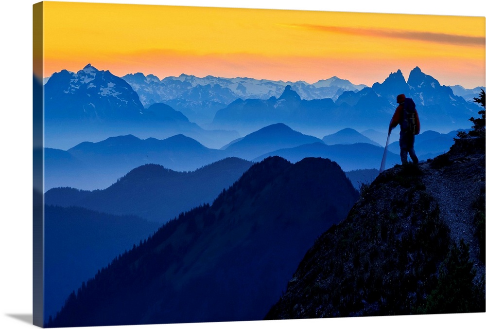 USA. Washington State. A backpacker decends from the Skyline Divide in the North Cascades near Mt. Baker at sunset. Promin...