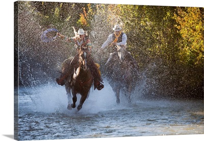 USA, Wyoming, Shell, Cowboy And Cowgirl On Horseback Running Through The River
