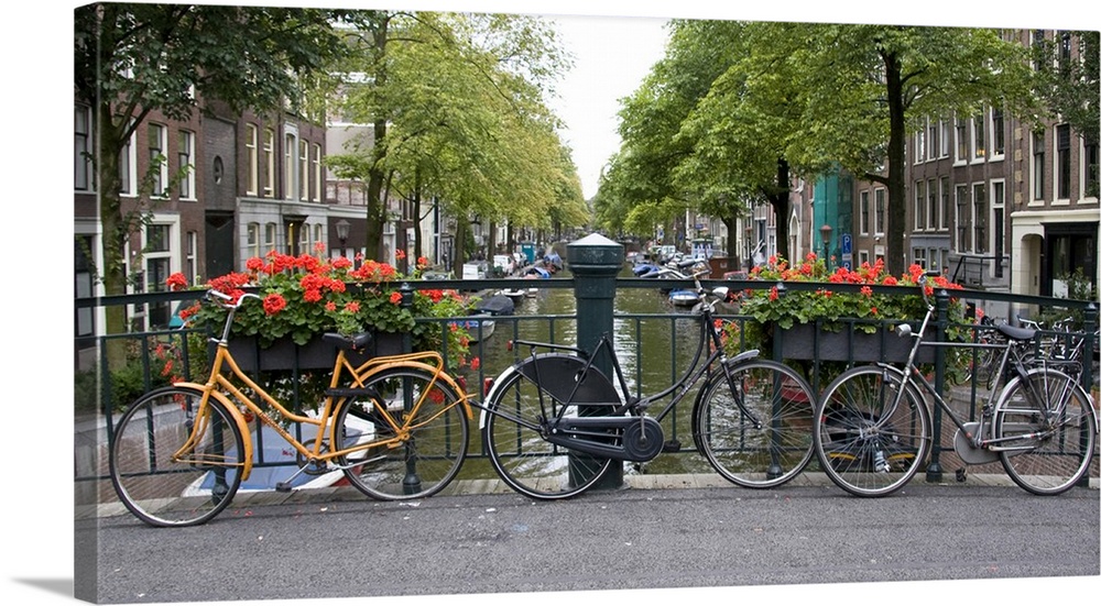 View from a bridge over a canal in Amsterdam with colorful bikes and red flowers