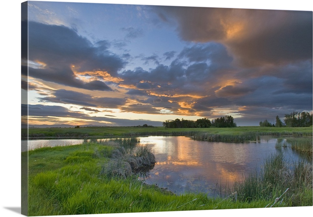 Vivid sunset clouds reflect into small pond at the Ninepipe Wildlife Management Area in the Mission Valley of Montana